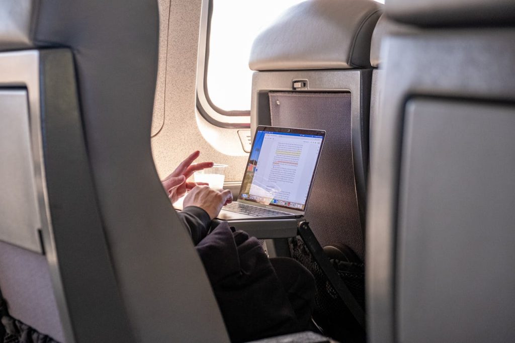 Passenger working on a laptop during flight, highlighting travel productivity.